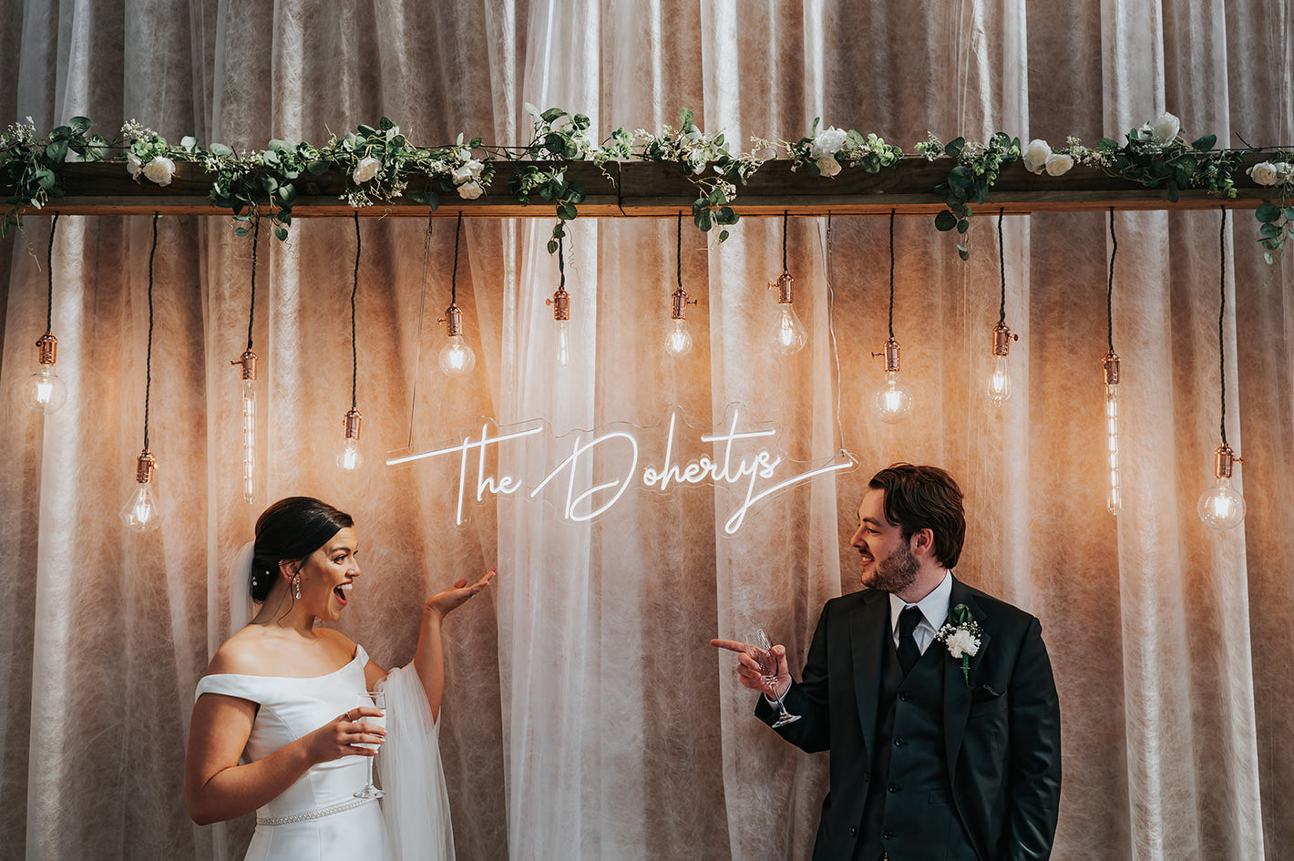 A custom LED neon sign hanging from a backdrop at a wedding that says the Dohertys which is the couples surname in Manchester, UK