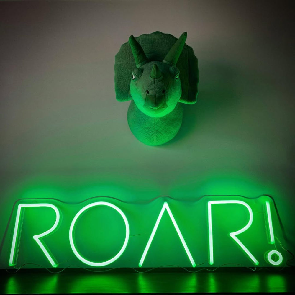Green dinosaur head mount on a gray wall with a neon 'ROAR!' sign below