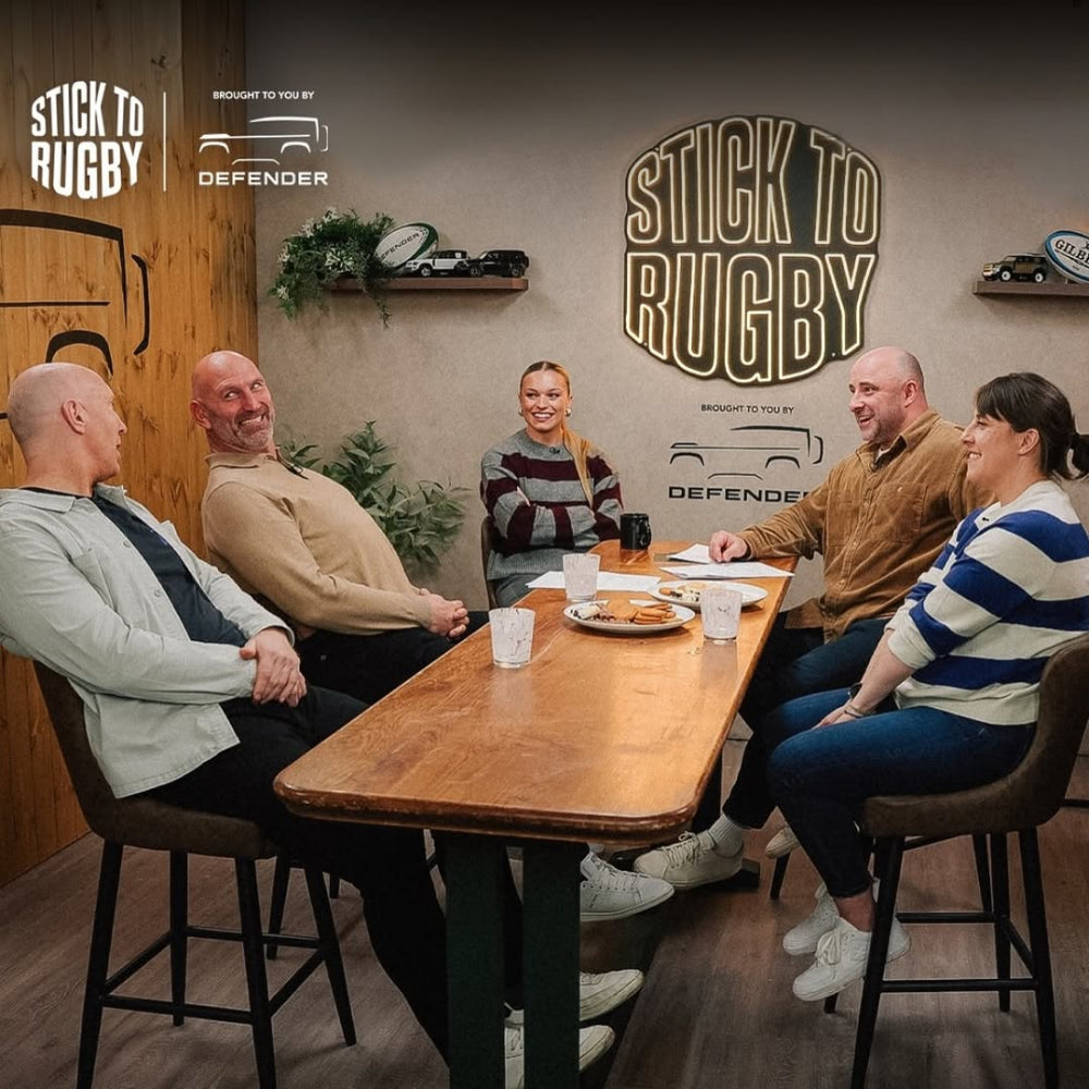 Group of people sitting around a table with 'Stick to Rugby' branding in the background.